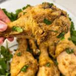 air fryer chicken drumstick being held above a plate of them