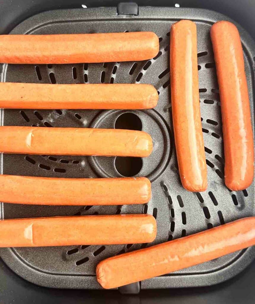 Hot dogs in the basket of an air fryer.