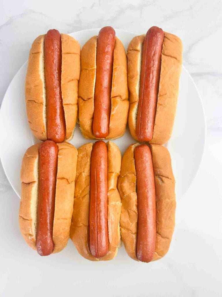 Cooked hot dogs in buns on a white plate.