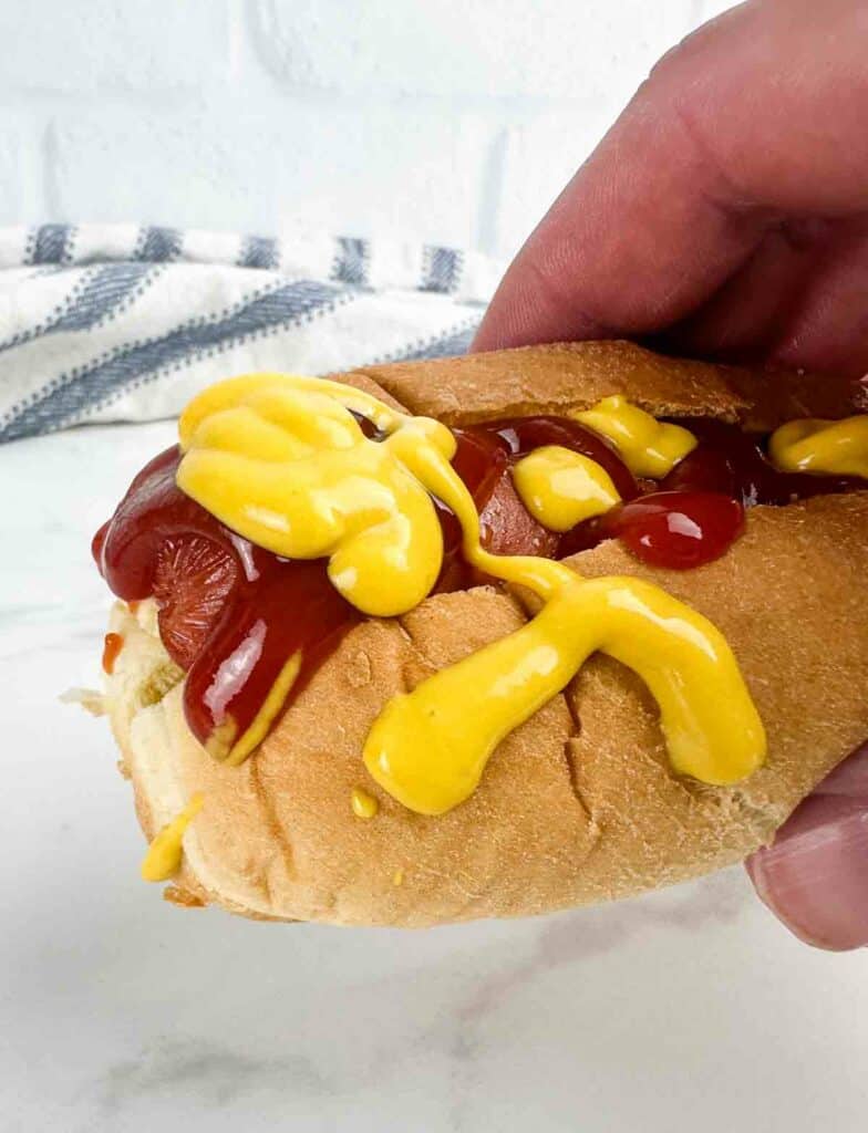 Fully loaded air fryer hot dog with mustard and ketchup on it.