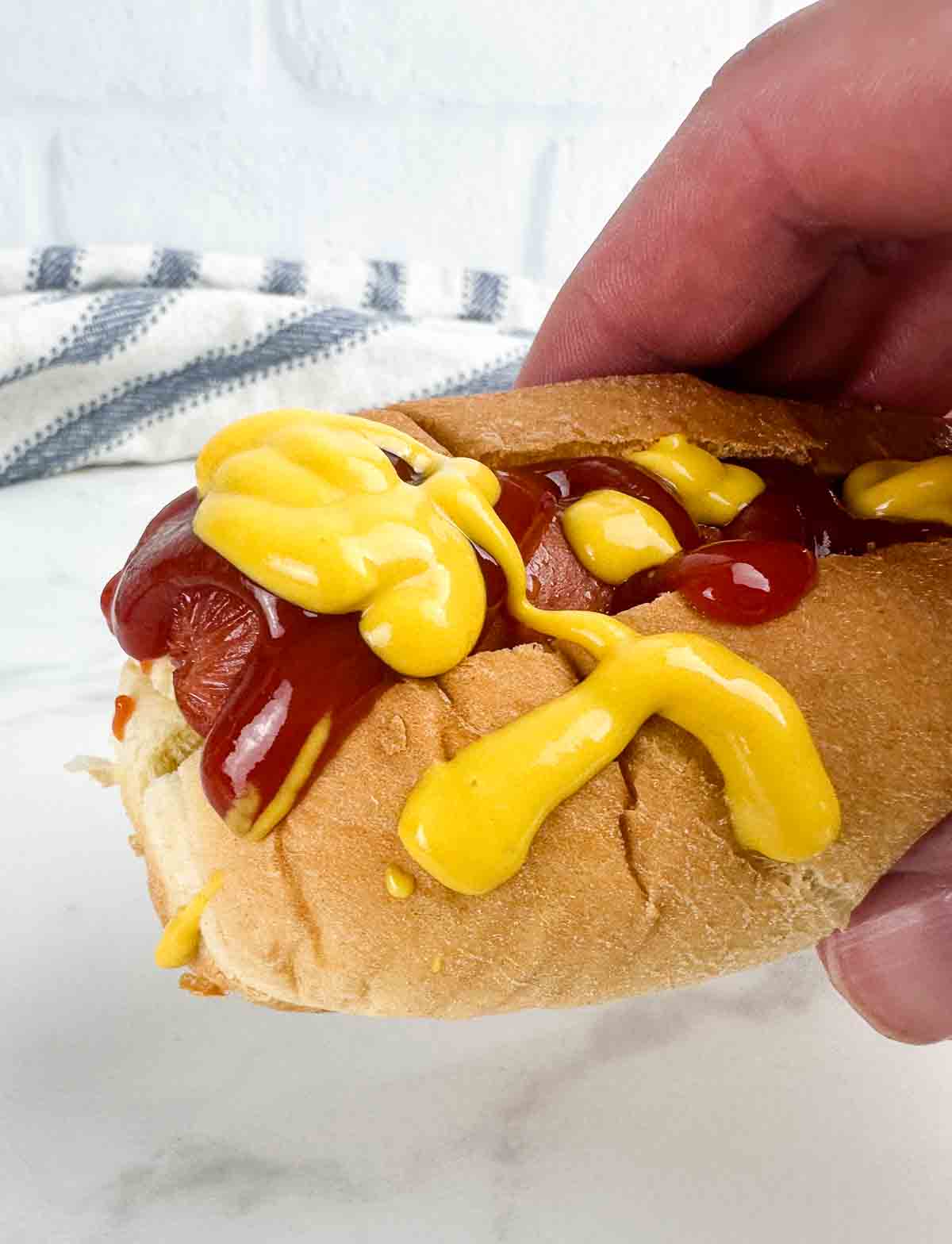 Fully loaded air fryer hot dog with mustard and ketchup on it.