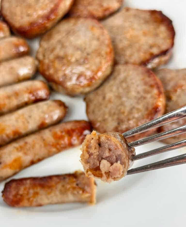 Ready to serve breakfast patties and links with a bite sized piece in a fork.