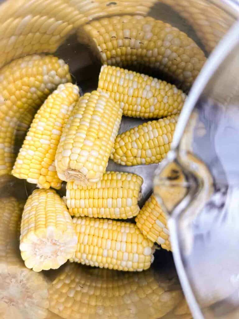 Pouring water on top of corn on the cob.